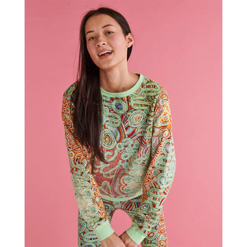 Close up front view of a model wearing a matching sweater and leggings in a green and red pattern.