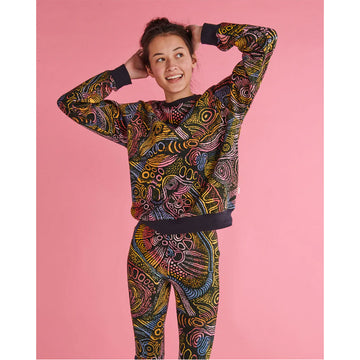 Front view of a model wearing a matching sweater and leggings printed with a colourful Indigenous pattern on a black background.