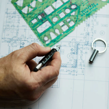 A multi tool with a pen, ruler and keyring attached to a blue and brown card.