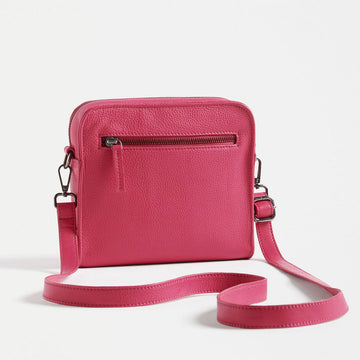 Front view of a cross body bag in hot pink with matching detachable straps and the ELK logo visible.