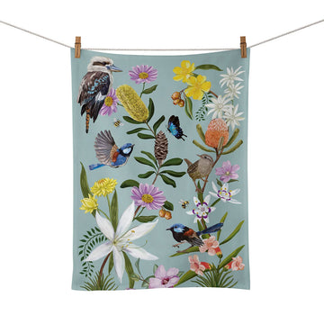 A tea towel illustrated with birds and flowers is hanging by pegs on a rope.