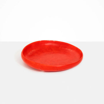 A large round shallow bowl made from red resin.