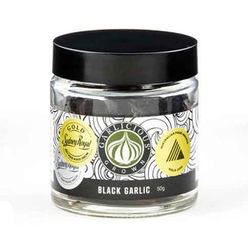 A clear jar with a wide product label on it with the title 'Black Garlic'.