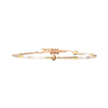 Gold and white beaded bracelet on a white background.