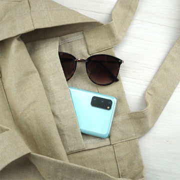 A calico tote bag printed with an illustration of wattle flowers, leaves and bees.