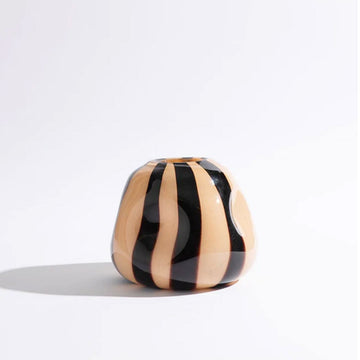 A glass vase with convex shapes and a black and nude striped pattern.