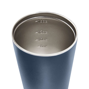 A tall travel mug in denim blue&nbsp;with a black lid and the text 'made by Fressko' on the bottom.