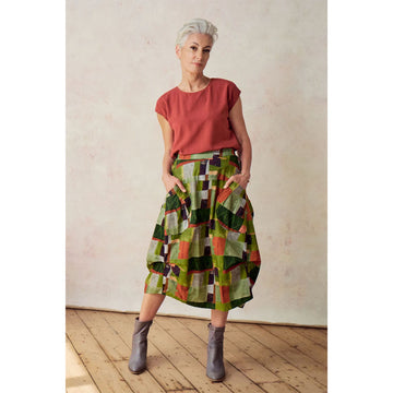 A skirt printed with a green and brown pattern with side pockets and side tucks.