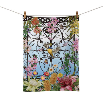 Decorative tea towel with floral and bird design hanging on a line.