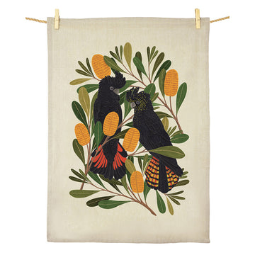 A cotton tea towel illustrated with two black cockatoos and banksia flowers.