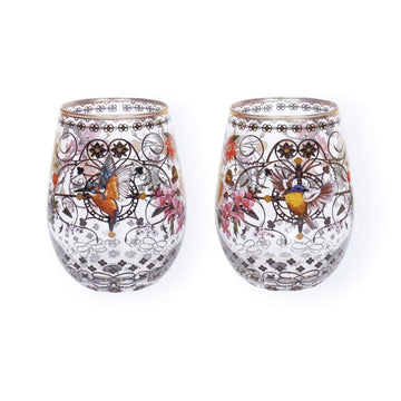 Two stemless wine glasses with decorative designs of birds and flowers on a white background.