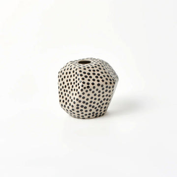 A small hexagon shaped vase in cream with black spots.