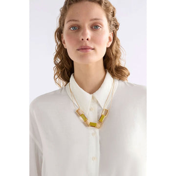 Necklace with geometric pendant on a light gray background.