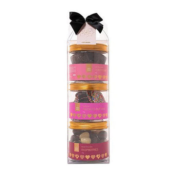 A clear cylinder packaged filled with three round containers of different chocolates. There is a black box on the top.
