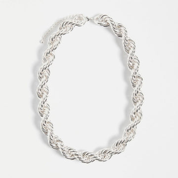 Silver chain necklace on a light gray background.