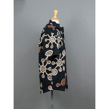 Front view of a black shirt with circular pattern on a mannequin against a gray background.