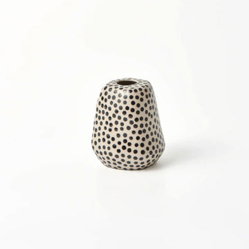 A small vase in cream with black spots.