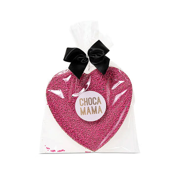 A heart shaped chocolate covered with pink sprinkles in clear packaging with a black bow at the top.