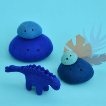 A cobalt blue stegosaurus made from felt surrounded by blue felt rocks.