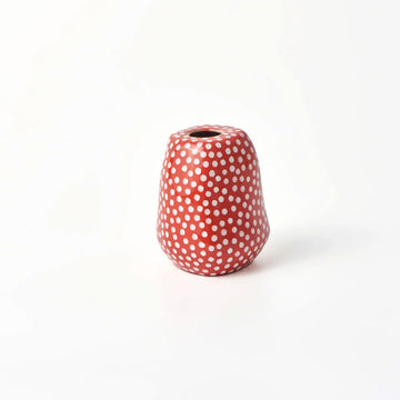 A small vase in red with cream spots.