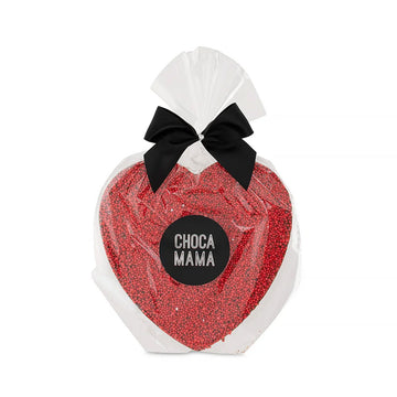 A heart shaped chocolate covered with red sprinkles in clear packaging with a black bow on top.