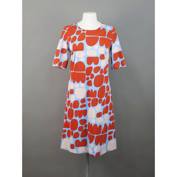 Front view of a dress with red and beige abstract pattern on a mannequin against a gray background.