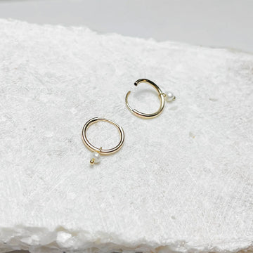 Gold hoop earrings on a textured white surface.