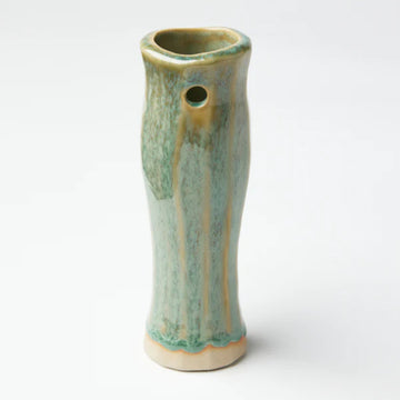 A tall skinny handcrafted vase in a green and yellow streaky colour.