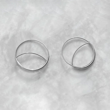 Pair of silver hoop earrings on a light gray textured background