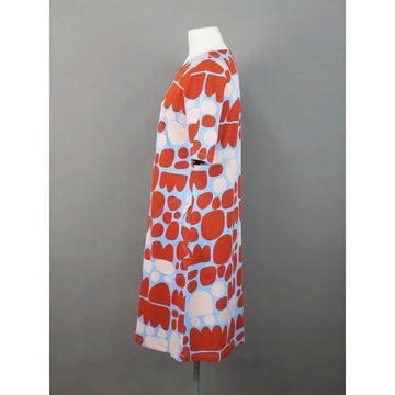 Front view of a dress with red and beige abstract pattern on a mannequin against a gray background.