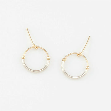 A pair of circle stud earrings in gold and silver.
