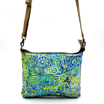 A leather cross body bag with a brown strap and printed with artwork by Cedric Varcoe in blue and green on the front.