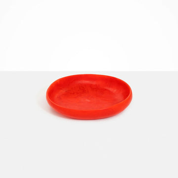 A round shallow bowl made from red resin.