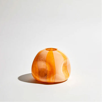 A glass vase with convex shapes and a dark and light orange striped pattern.