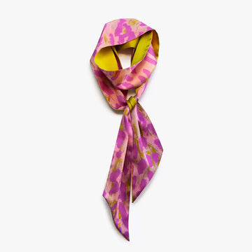 A silk scarf tied up in a knot and printed with artwork by Rosie Tarku in pink.