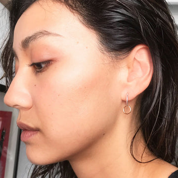 Gold hoop earrings on a textured white surface.