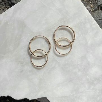 Pair of gold hoop earrings on a textured white surface.