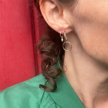 Pair of gold hoop earrings on a textured white surface.