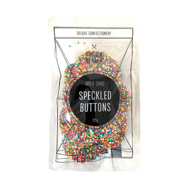 A clear bag filled with speckled chocolate and the titled 'Speckled Buttons' in a black circle on the front.