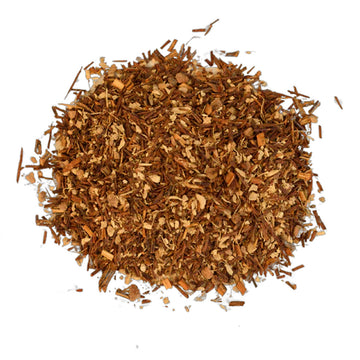 A purple box with white writing, loose tea in a wooden bowl, cinnamon sticks and a ginger root.