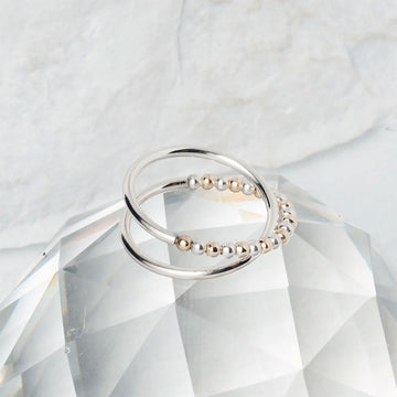 A ring with a cross over and beaded design on a clear crystal surface.