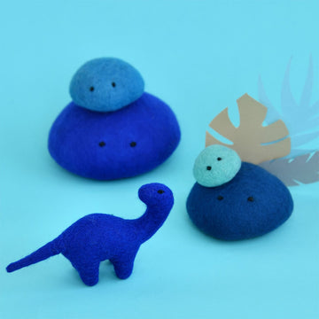 A cobalt blue brontosaurus  made from felt surrounded by blue felt rocks in different sizes and shades.