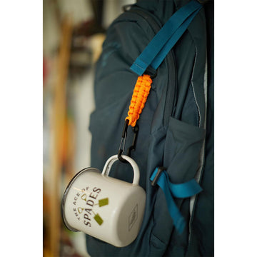 A multi tool with a orange cord attached to a brown and black card.