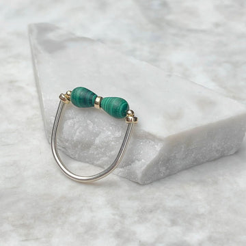 A silver ring with malachite stones along the top.