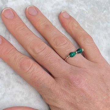 A silver ring with malachite stones along the top.
