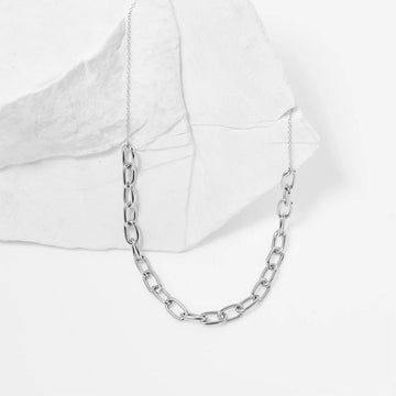 Silver chain necklace on a white textured background.