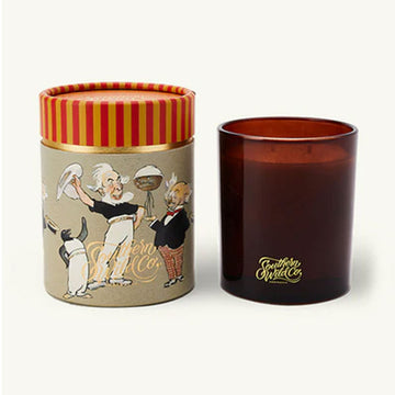 A brown glass candle next to a cylinder box with illustrations from the Magic Pudding.