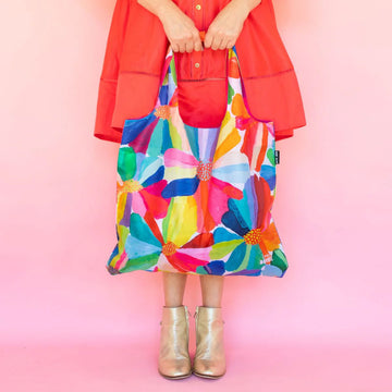 A reusable shopping bag printed with artwork of colourful flowers by Lordy Dordie.