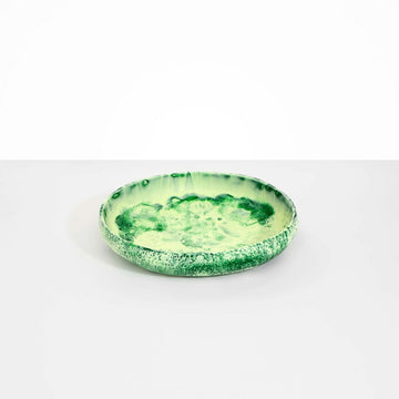 A round shallow bowl made from green resin.