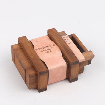 A brown cardboard box with a clear window on the front showing a wooden box inside with a label that says 'Mysterious Secret Box'.